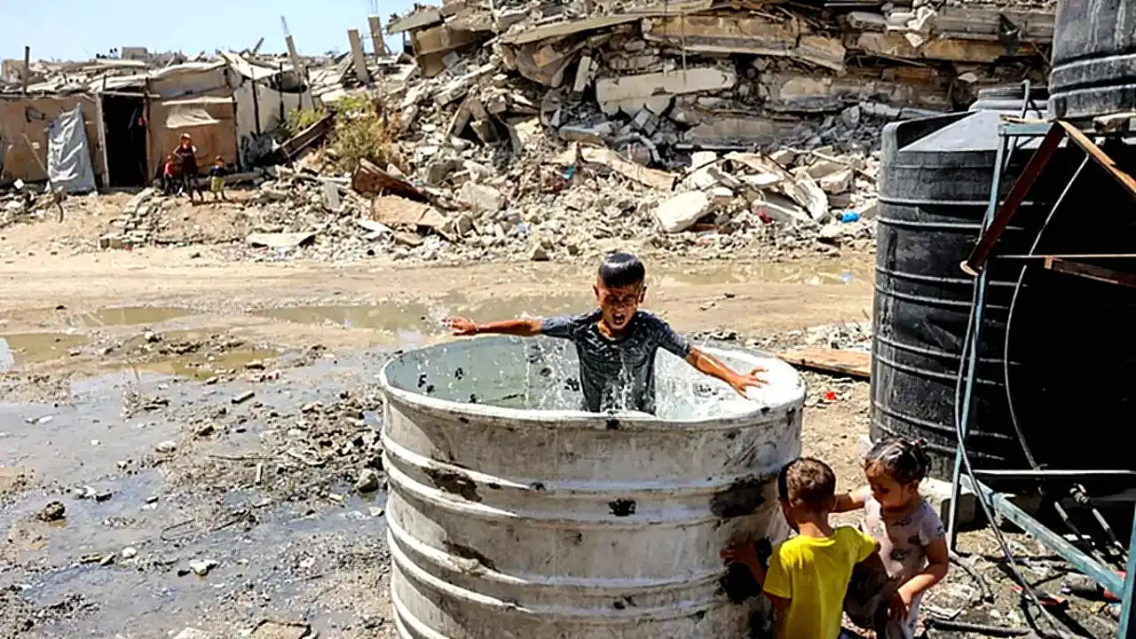تحويل حكومي غزة - طفل فلسطيني يلعب في حاوية ماء بجانب خزان